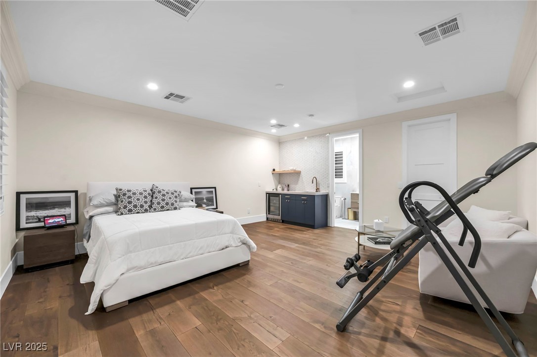 8032 Spring Buck Court Las Vegas, NV 89129 - Photo 39 of 41 Bedroom featuring dark engineered wood flooring, ornamental molding, recessed lighting, and wine cooler