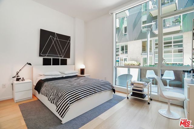 a bedroom with a bed wooden floor and a large window