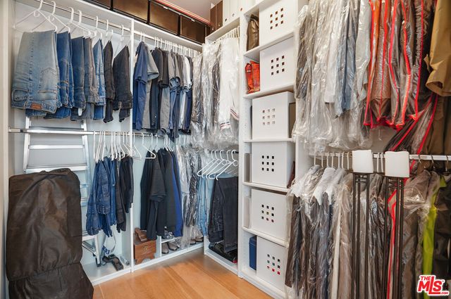 a view of walk in closet with clothes and shoes