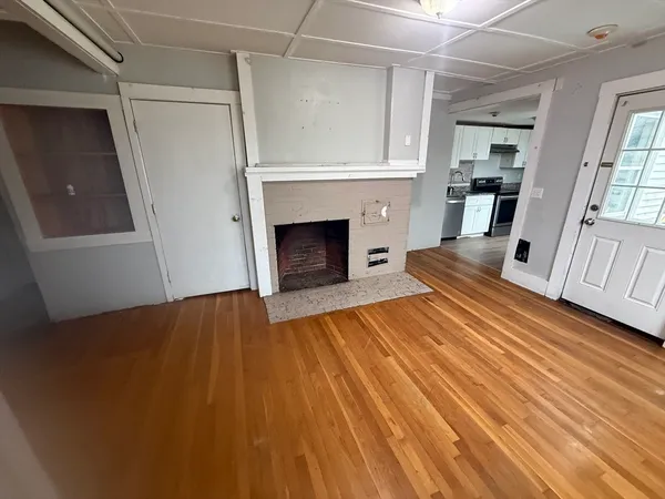 a view of a livingroom with wooden floor and a fireplace