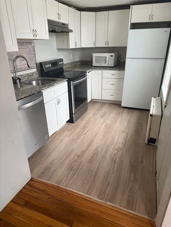 a kitchen with granite countertop a sink cabinets and stainless steel appliances
