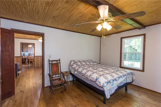 a bedroom with a bed and a dresser with wooden floor