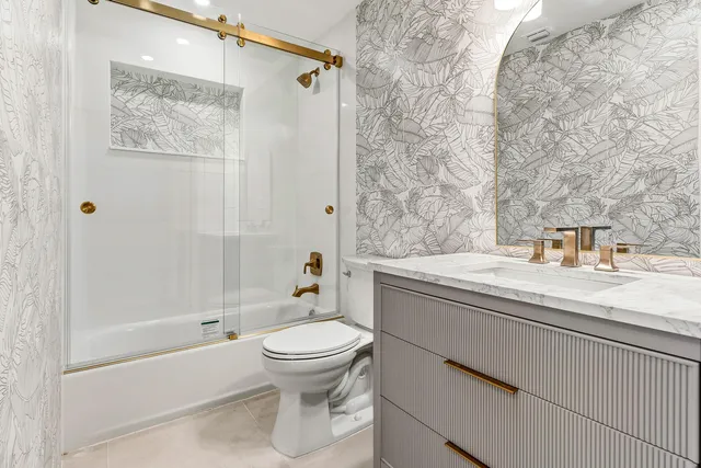 a bathroom with a granite countertop bathtub sink vanity mirror and toilet