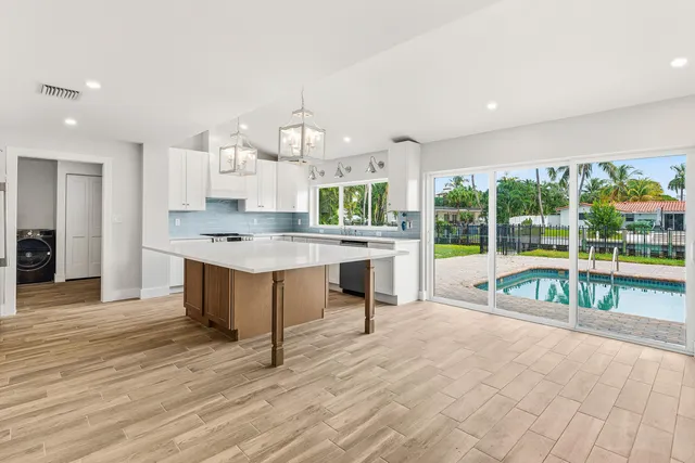 a large kitchen with kitchen island a large counter top stainless steel appliances and cabinets