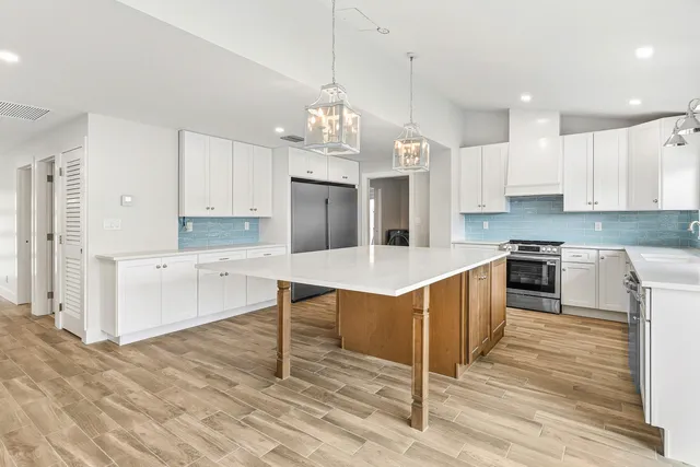 a large kitchen with granite countertop a stove top oven a sink a counter space and cabinets