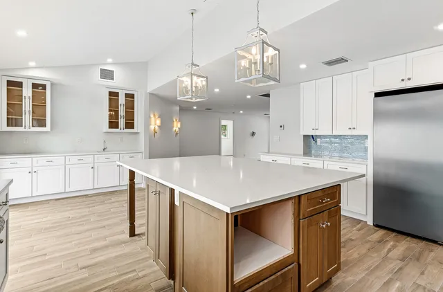 a kitchen with kitchen island a island a stove a refrigerator and a sink
