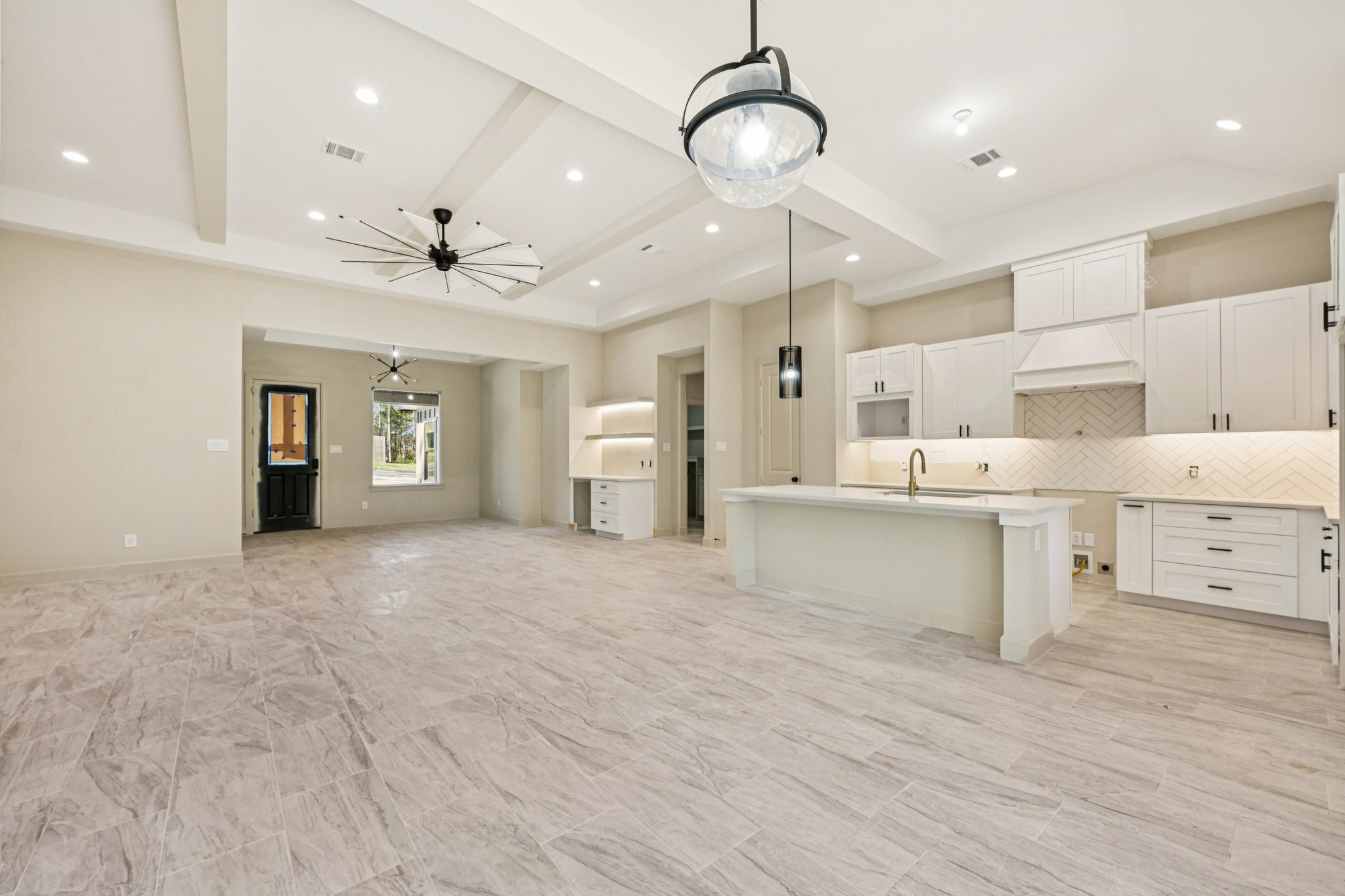 15132 Coaltown Road Willis, TX 77378 - Photo 2 of 29 Spacious open-concept living area features a modern kitchen with a large island, elegant white cabinetry, and contemporary pendant lighting.