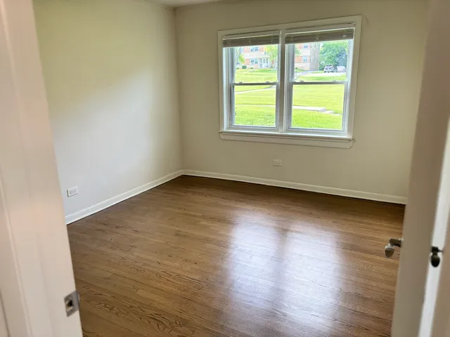 an empty room with wooden floor and a window
