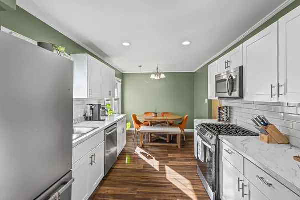 a kitchen with stainless steel appliances a stove top oven a sink a refrigerator white cabinets and wooden floor