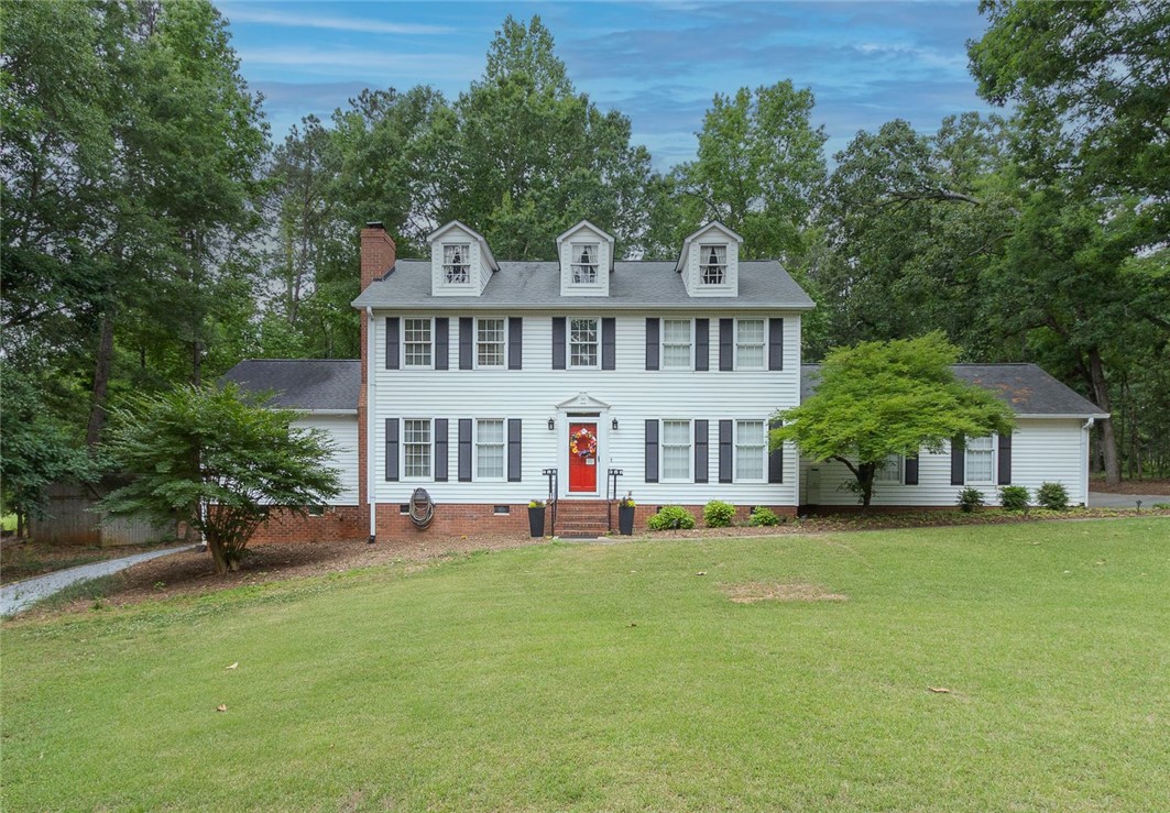 A well-maintained facade with striking dormer windows and a vibrant red entry door.