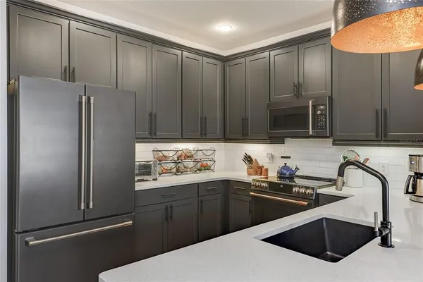 a kitchen with stainless steel appliances a sink a stove a refrigerator and cabinets