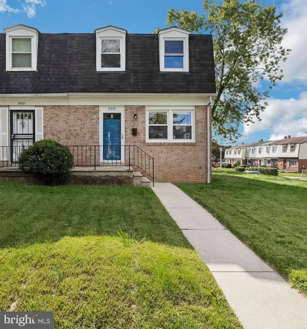 a brick house with a yard plants and big trees