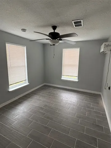 an empty room with windows and fan