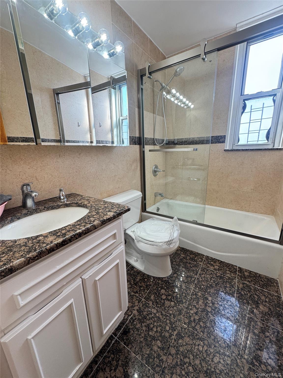 41-40 Union Street, Unit 16D Queens, NY 11355 - Photo 10 of 12 a bathroom with a granite countertop sink a toilet a mirror and shower