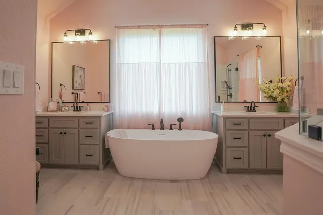 a spacious bathroom with a double vanity sink mirror and bathtub
