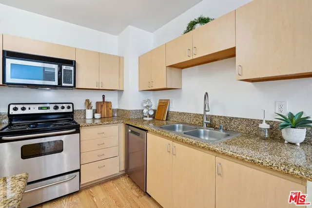 a kitchen with granite countertop a sink stainless steel appliances and cabinets