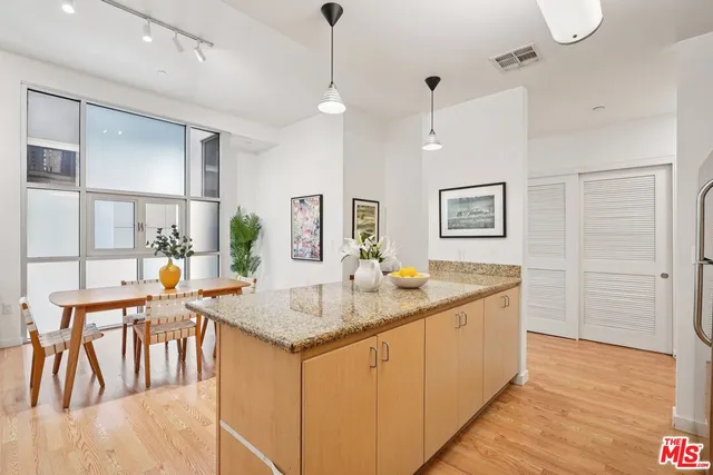 a dining hall with stainless steel appliances granite countertop wooden floor a dining table and chairs