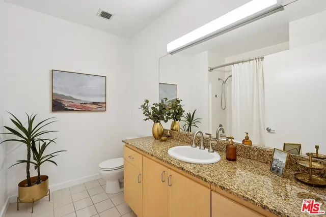 a bathroom with a granite countertop sink a toilet and a mirror