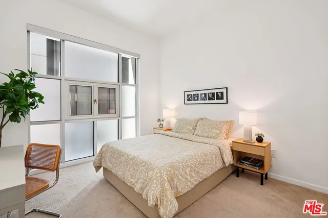 a bedroom with a bed and a potted plant on the dresser
