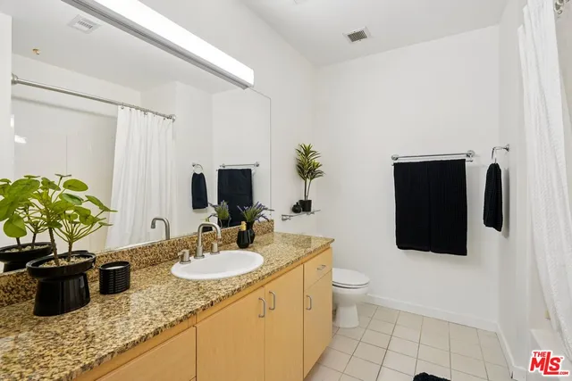 a bathroom with a granite countertop sink a toilet and mirror