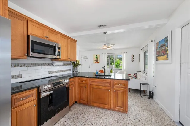 a kitchen with stainless steel appliances granite countertop a refrigerator a stove and a sink with wooden floor