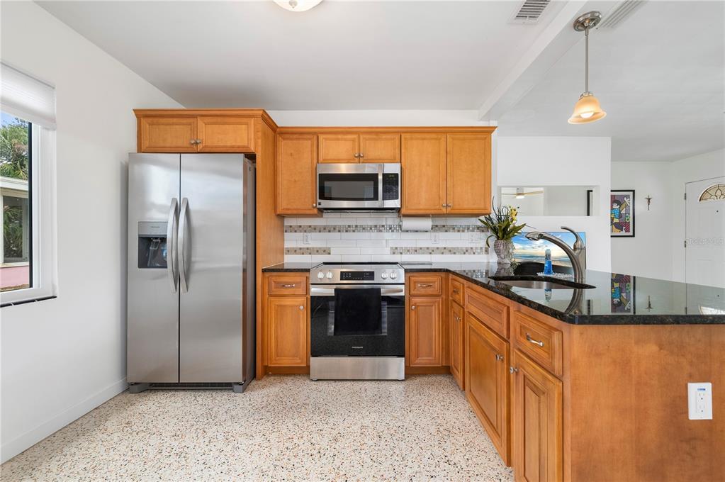 624 West Virginia Avenue Punta Gorda, FL 33950 - Photo 34 of 45 a kitchen with stainless steel appliances granite countertop a refrigerator a stove and a sink with wooden floor