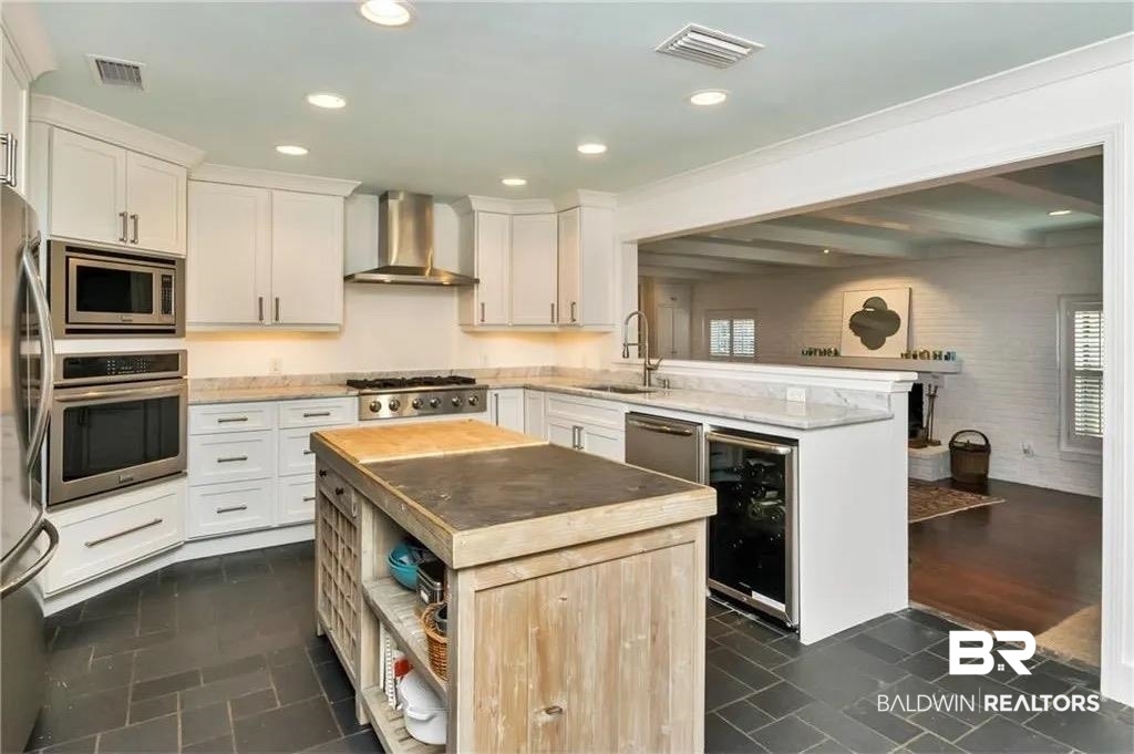 451 Ridgelawn Drive West Mobile, AL 36608 - Photo 36 of 41 Kitchen featuring appliances with stainless steel finishes, a sink, wall chimney exhaust hood, a peninsula, and wine cooler