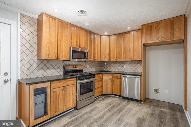 a kitchen with stainless steel appliances granite countertop a stove a sink and a microwave