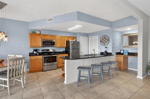 a kitchen with stainless steel appliances kitchen island granite countertop a table chairs and a refrigerator