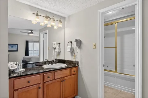 a bathroom with a granite countertop sink a large mirror and a shower