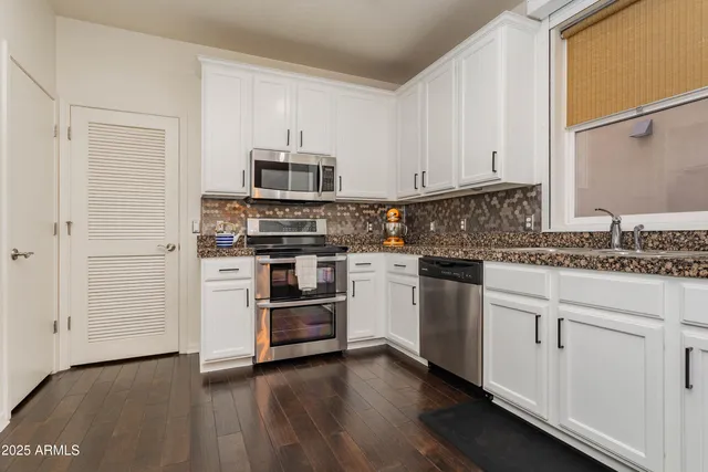 a kitchen with granite countertop white cabinets and stainless steel appliances