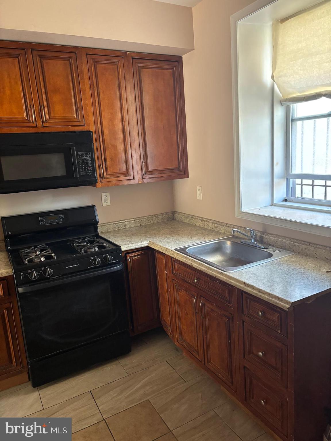 2328 East Madison Street Baltimore, MD 21205 - Photo 3 of 10 a kitchen with granite countertop stainless steel appliances a stove a sink and a microwave