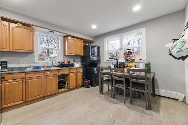 a open kitchen with stainless steel appliances granite countertop a stove top oven a sink a dining table and chairs with wooden floor