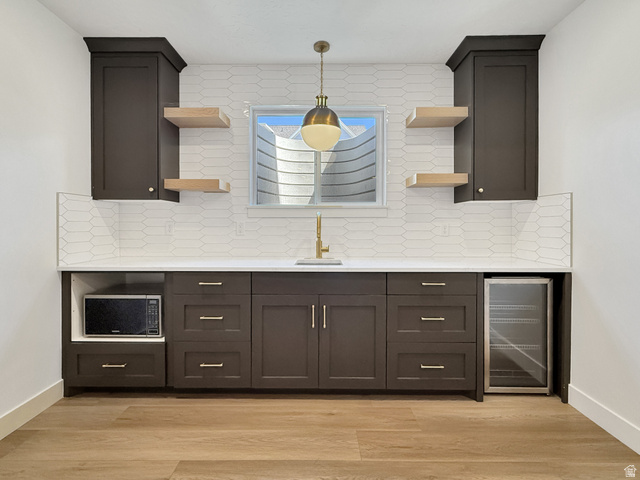 916 Rocky Mountain Way Elk Ridge, UT 84651 - Photo 41 of 54 Kitchen with open shelves, wine cooler, decorative backsplash, light stone counters, and light wood finished floors