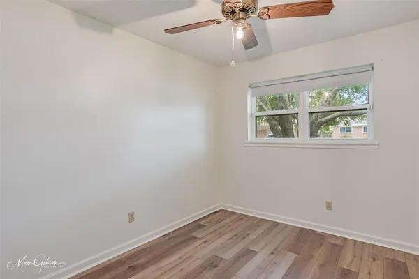 an empty room with a window and ceiling fan