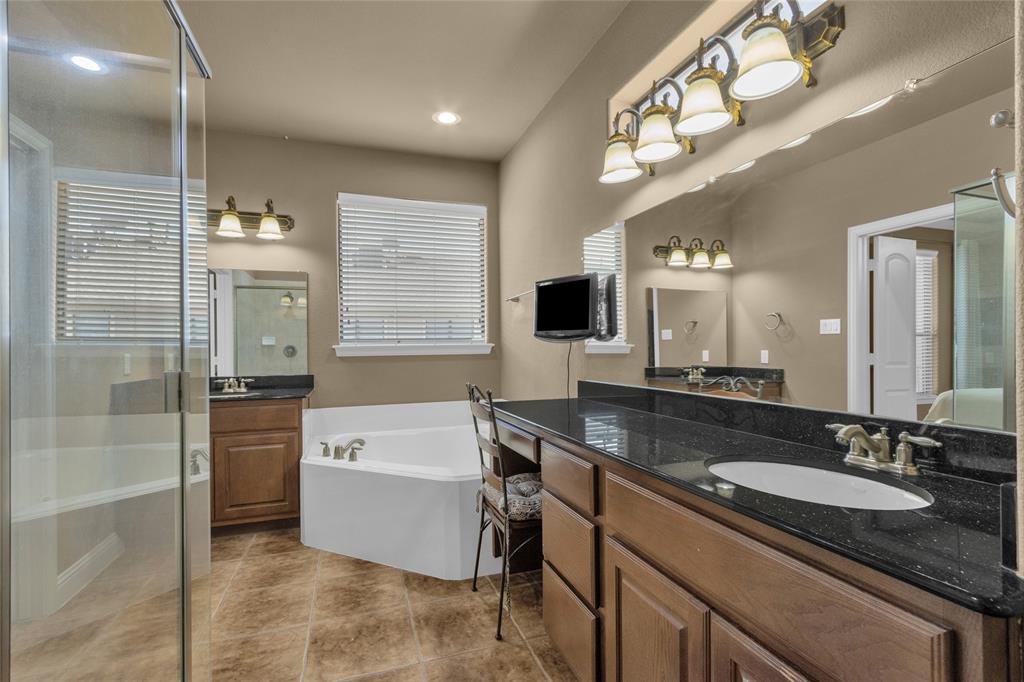 5724 Robbie Road Plano, TX 75024 - Photo 25 of 29 a bathroom with a granite countertop sink mirror and bathtub