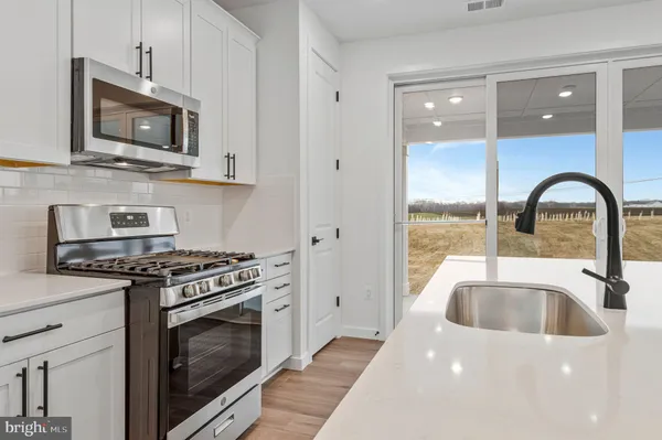 a kitchen with stainless steel appliances white cabinets and a stove a oven with wooden floor