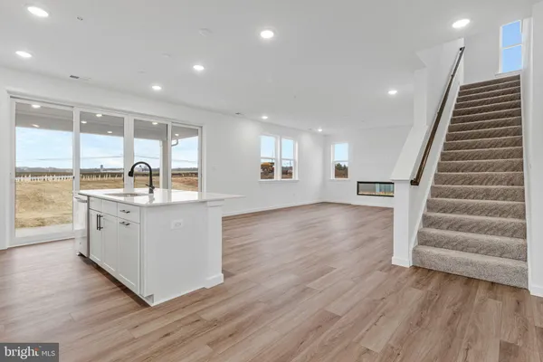 a kitchen with stainless steel appliances granite countertop a refrigerator a sink a stove a microwave and wooden floor
