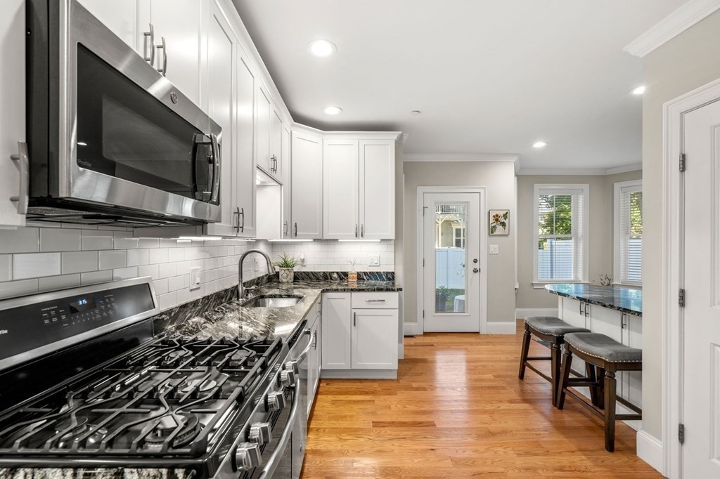 25 Cherry Street, Unit 3 Danvers, MA 01923 - Photo 7 of 27 a kitchen with stainless steel appliances a stove a microwave and white cabinets