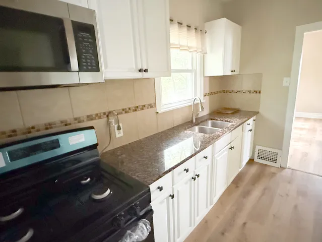 a kitchen with granite countertop a stove a sink and a microwave