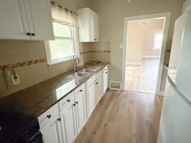 a kitchen with granite countertop a refrigerator a sink and a window