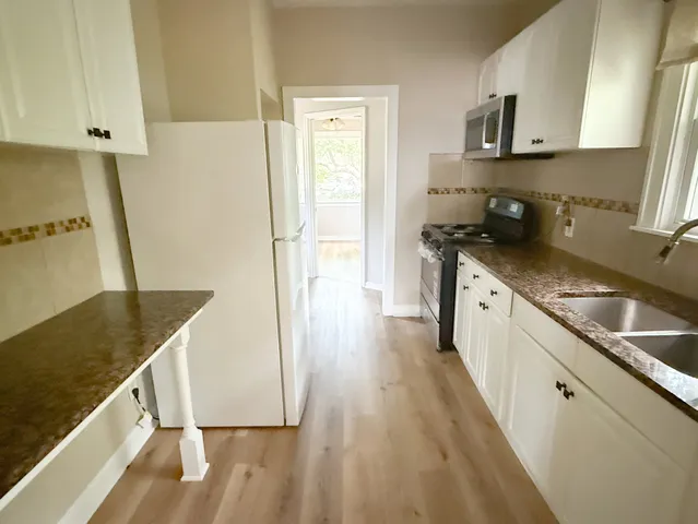 a kitchen with granite countertop a sink a stove and refrigerator