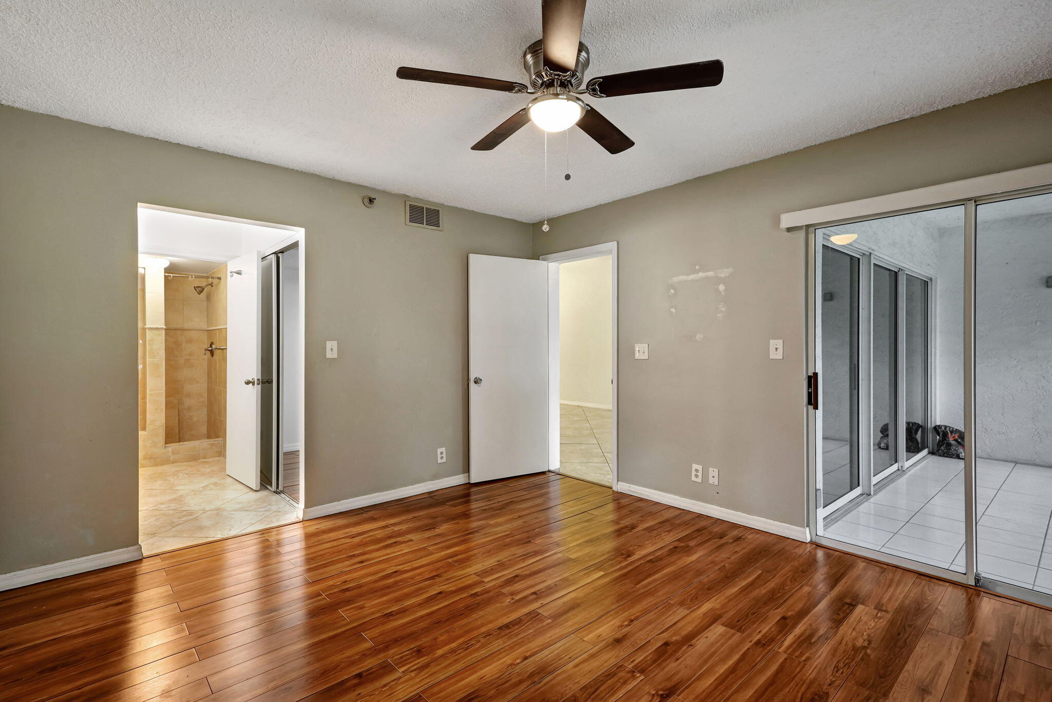 320 Northwest 67th Street, Unit C207 Boca Raton, FL 33487 - Photo 17 of 39 an empty room with wooden floor and ceiling fan