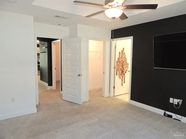 a view of an empty room with window and chandelier fan