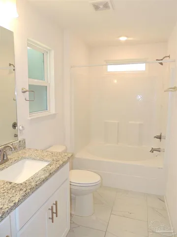 a bathroom with a granite countertop sink a toilet and shower