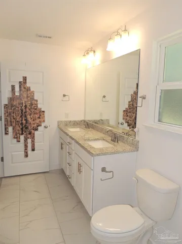 a spacious bathroom with a granite countertop sink a toilet and a mirror