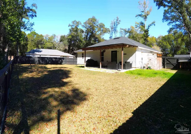 a view of a house with floor to ceiling windows and a yard