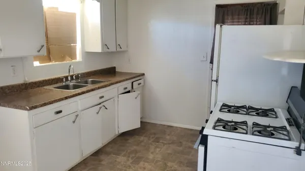 a kitchen with granite countertop a sink stove and cabinets