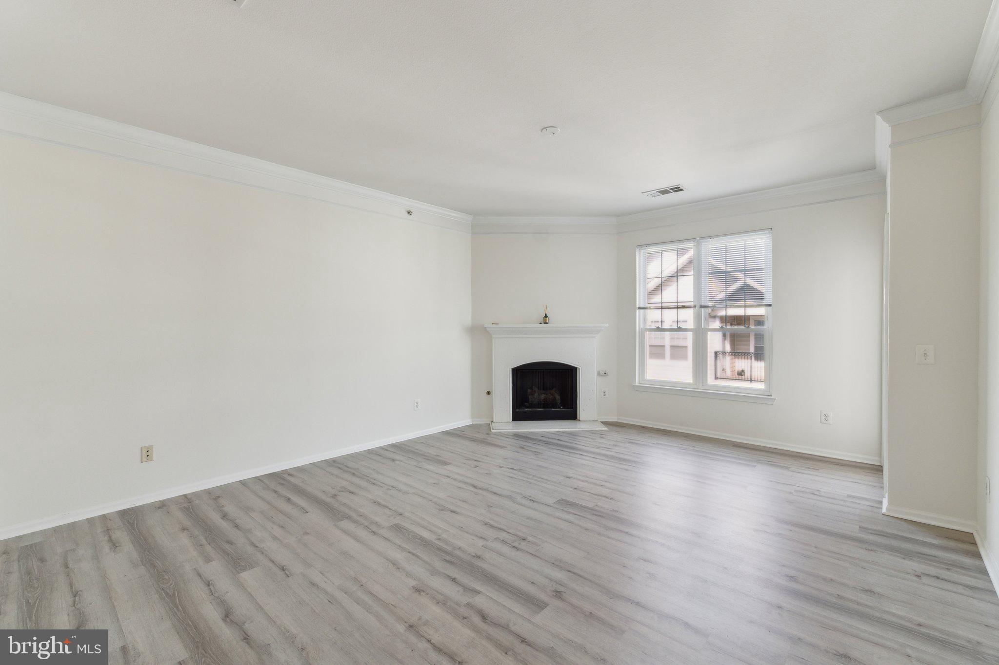 1591 Spring Gate Dr., Unit 3415 McLean, VA 22102 - Photo 3 of 20 an empty room with wooden floor and fireplace