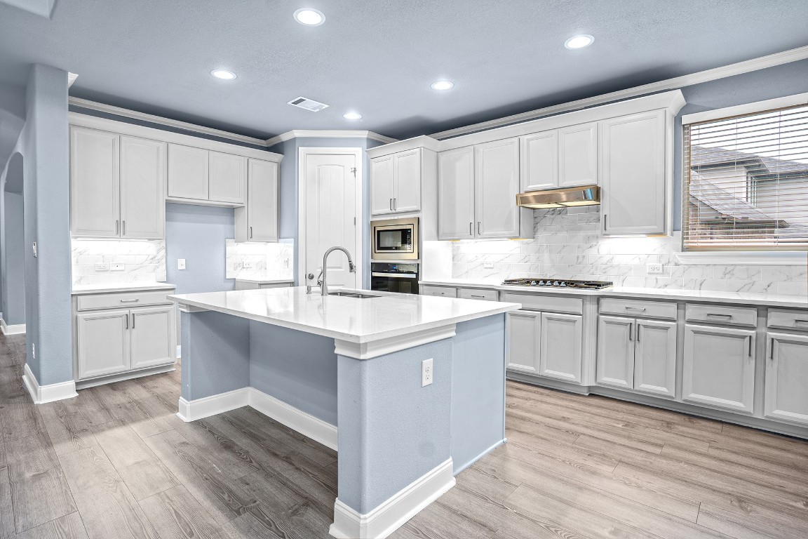 2328 Blended Tree Ranch Drive Leander, TX 78641 - Photo 12 of 30 a kitchen with kitchen island granite countertop a sink cabinets and wooden floor